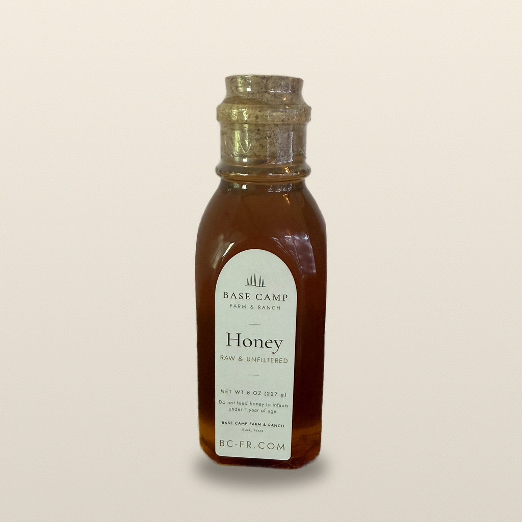 Base Camp raw honey 8 oz jar on a warm neutral backdrop