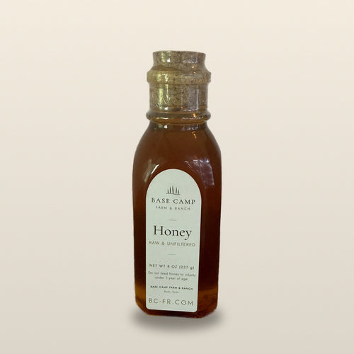 Base Camp raw honey 8 oz jar on a warm neutral backdrop